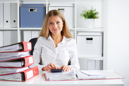 Smiling female CFO doing calculations at desk in office